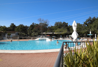 Piscina exterior en Camping Bijela Uvala, Istria, Croacia, con tumbonas y sombrillas bajo un cielo despejado.