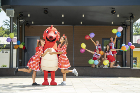 Niños con disfraces coloridos y una mascota en el escenario con globos en Camping Bijela Uvala, Istria, Croacia.