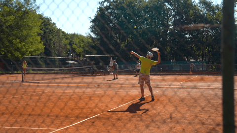 Persone che giocano a tennis su un campo in terra rossa al Camping Bijela Uvala, Istria, Croazia.