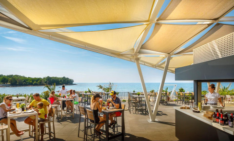 Restaurant extérieur au Camping Aminess Maravea en Istrie, Croatie, vue sur mer et clients détendus.