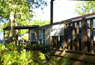 Træhytte med skiltet 'Easytent' på Camping Bijela Uvala i Istrien, Kroatien, omgivet af grøn beplantning.
