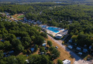 Luftfoto af Camping Bijela Uvala i Istrien, Kroatien, med swimmingpool, campingvogne og masser af træer.