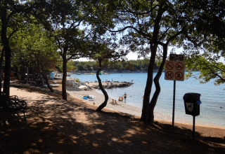 Skygget sti med udsigt til strand og hav ved Camping Bijela Uvala, feriepark i Istrien, Kroatien.