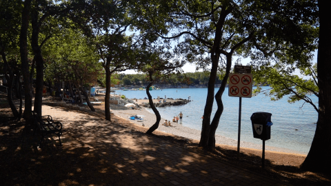 Skygget sti med udsigt til strand og hav ved Camping Bijela Uvala, feriepark i Istrien, Kroatien.