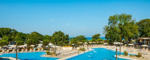 Area piscina del Camping Aminess Maravea, Istria, Croazia, con lettini, alberi e vista sul mare.
