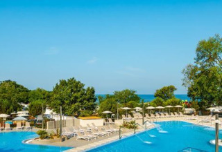 Area piscina del Camping Aminess Maravea, Istria, Croazia, con lettini, alberi e vista sul mare.