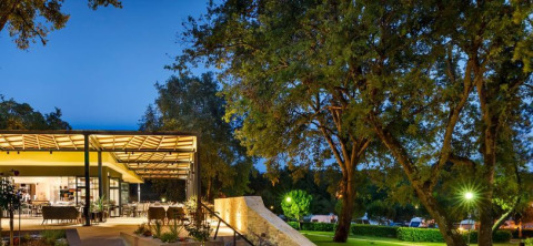 Offenes Restaurant und beleuchtete Bäume im Camping Aminess Maravea Ferienpark, Istrien, Kroatien bei Abenddämmerung.