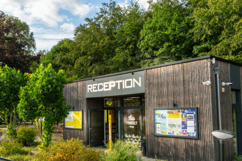 Receptiegebouw van hu Birkelt Village vakantiepark in Mersch, Luxemburg, omgeven door groen.