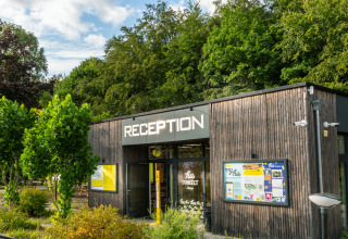Receptionen ved hu Birkelt Village feriepark i Mersch, Luxembourg, omgivet af grønne træer.