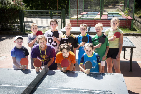 Bambini e ragazzi con racchette da ping pong all'aria aperta al villaggio hu Birkelt di Mersch, Lussemburgo.