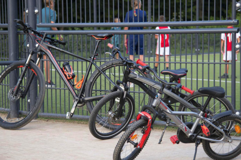 Dos bicicletas apoyadas en una valla junto a un campo de fútbol en hu Birkelt Village, parque vacacional en Mersch, Luxemburgo.