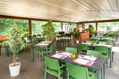 Modern restaurant met groene stoelen en planten in hu Birkelt Village vakantiepark in Mersch, Luxemburg.