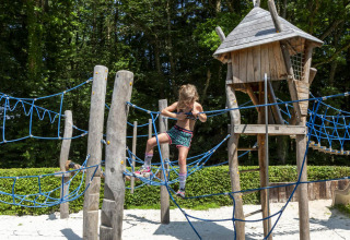 Niño trepando en una estructura de madera y cuerda en el parque hu Birkelt Village, Mersch, Luxemburgo.