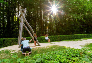 Børn leger og svinger på en zipline i en solrig park ved hu Birkelt Village i Mersch, Luxembourg.