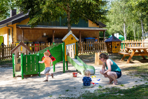 Des enfants jouent avec un adulte sur une aire de jeux au hu Birkelt Village, parc de vacances à Mersch, Luxembourg.