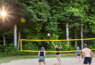 Mensen spelen volleybal op een zandveld in het bos bij hu Birkelt Village in Mersch, Luxemburg.