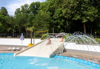 Children playing on a water slide at the pool in hu Birkelt Village holiday park, Mersch, Luxembourg.