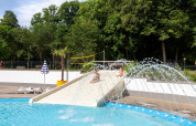 Children playing on a water slide at the pool in hu Birkelt Village holiday park, Mersch, Luxembourg.