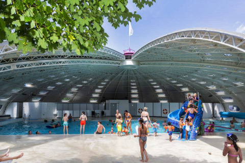 Families enjoy the covered swimming pool and playful blue slide at hu Birkelt Village, Mersch, Luxembourg.