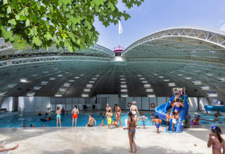 Families enjoy the covered swimming pool and playful blue slide at hu Birkelt Village, Mersch, Luxembourg.