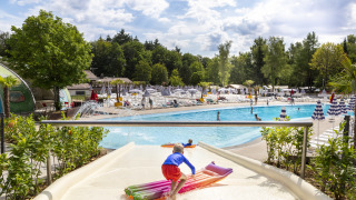Kind op een waterglijbaan met luchtbed bij het buitenzwembad in hu Birkelt Village, Luxemburg.