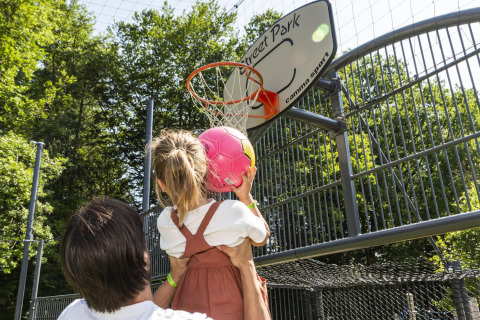 An adult helps a child shoot a pink ball into a basketball hoop at hu Birkelt Village in Mersch, Luxembourg.