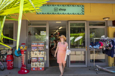 Vrouw verlaat winkel bij hu Birkelt Village vakantiepark in Mersch, Luxemburg, met zomerspullen buiten.