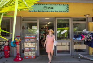 Kvinde forlader butik i hu Birkelt Village feriepark i Mersch, Luxembourg, omgivet af sommerartikler.