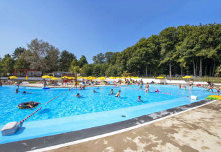 Piscina del parque vacacional hu Birkelt Village en Mersch, Luxemburgo, con huéspedes y sombrillas amarillas.