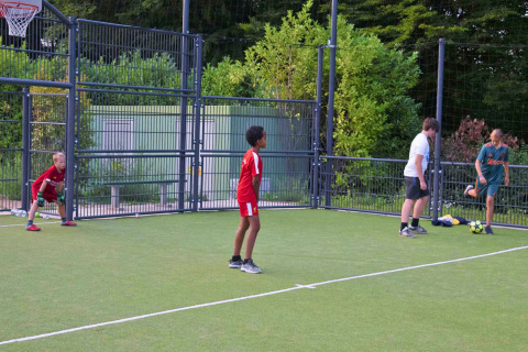 Kinderen en volwassenen voetballen op een buitenveld bij hu Birkelt Village vakantiepark in Mersch, Luxemburg.