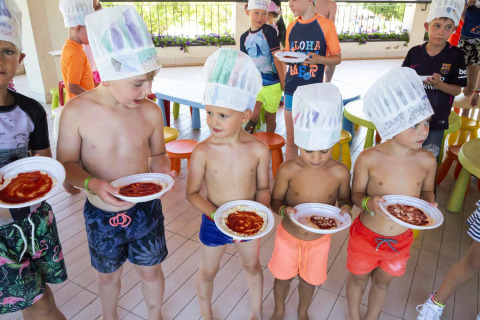 Kinderen in badkleding en kokshoed maken samen eten in hu Birkelt Village vakantiepark in Mersch, Luxemburg.