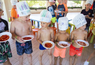 Kinderen in zwemkledij en koksmutsen koken samen in hu Birkelt Village vakantiepark in Mersch, Luxemburg.