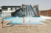 Børn leger i swimmingpoolen ved en stor vandrutsjebane i Løkken Klit Camping, Nordjylland, Danmark.