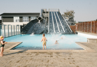Kinderen spelen in het zwembad met een grote waterglijbaan bij Løkken Klit Camping, Noord-Jutland, Denemarken.
