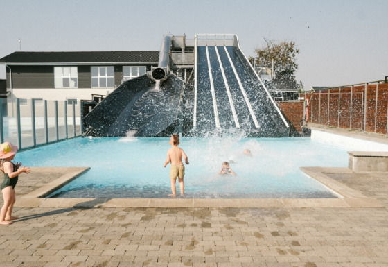 Børn leger i swimmingpoolen ved en stor vandrutsjebane i Løkken Klit Camping, Nordjylland, Danmark.