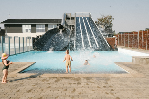 Børn leger i swimmingpoolen ved en stor vandrutsjebane i Løkken Klit Camping, Nordjylland, Danmark.