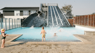 Børn leger i swimmingpoolen ved en stor vandrutsjebane i Løkken Klit Camping, Nordjylland, Danmark.