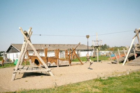 Speelplein met houten schommel en kabelbaan bij Løkken Klit Camping vakantiepark in Noord-Jutland, Denemarken.