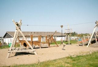 Parque infantil con columpio de madera y tirolina en Løkken Klit Camping, parque vacacional en Jutlandia del Norte, Dinamarca.