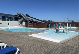 Zona de piscina exterior con tobogán de agua y juegos en Løkken Klit Camping, Jutlandia del Norte, Dinamarca.