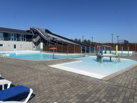 Zona de piscina exterior con tobogán de agua y juegos en Løkken Klit Camping, Jutlandia del Norte, Dinamarca.