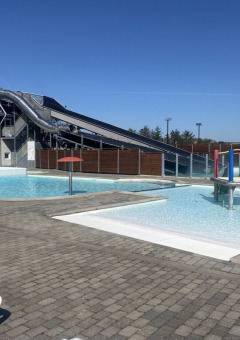 Außenpoolbereich mit Wasserrutsche und Spielplatz im Løkken Klit Camping, Nordjütland, Dänemark.