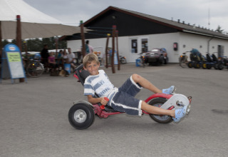 Ragazzo su un triciclo davanti a un villaggio turistico al Løkken Klit Camping in Jutland settentrionale, Danimarca.