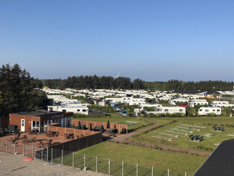 Overzicht van Løkken Klit Camping in Noord-Jutland, Denemarken met stacaravans en een restaurantterras.