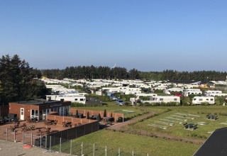 Overzicht van Løkken Klit Camping in Noord-Jutland, Denemarken met stacaravans en een restaurantterras.