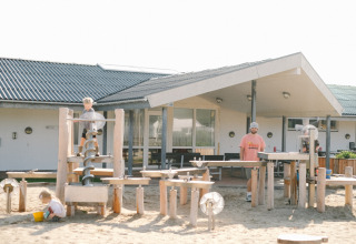 Børn leger på legeplads ved Løkken Klit Camping i Nordjylland, Danmark, med voksen tilsyn i baggrunden.
