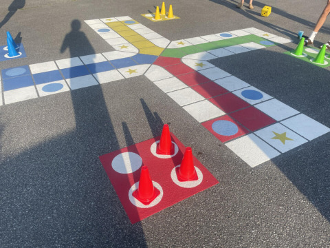 Juego de mesa al aire libre con conos de colores y dados sobre asfalto en Løkken Klit Camping, Dinamarca.
