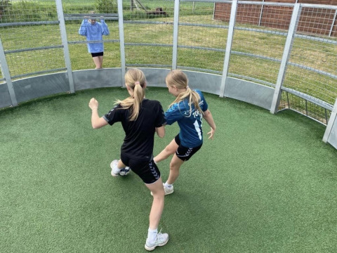 Zwei Mädchen spielen Ball in einer runden Arena bei Løkken Klit Camping in Nordjütland, Dänemark.