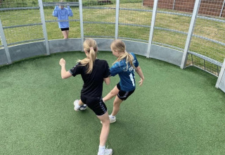 Two girls play ball in a circular enclosure at Løkken Klit Camping in North Jutland, Denmark.