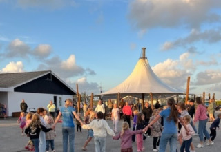 Bambini e adulti che ballano in cerchio a Løkken Klit Camping, parco vacanze nel Nord Jutland, Danimarca.